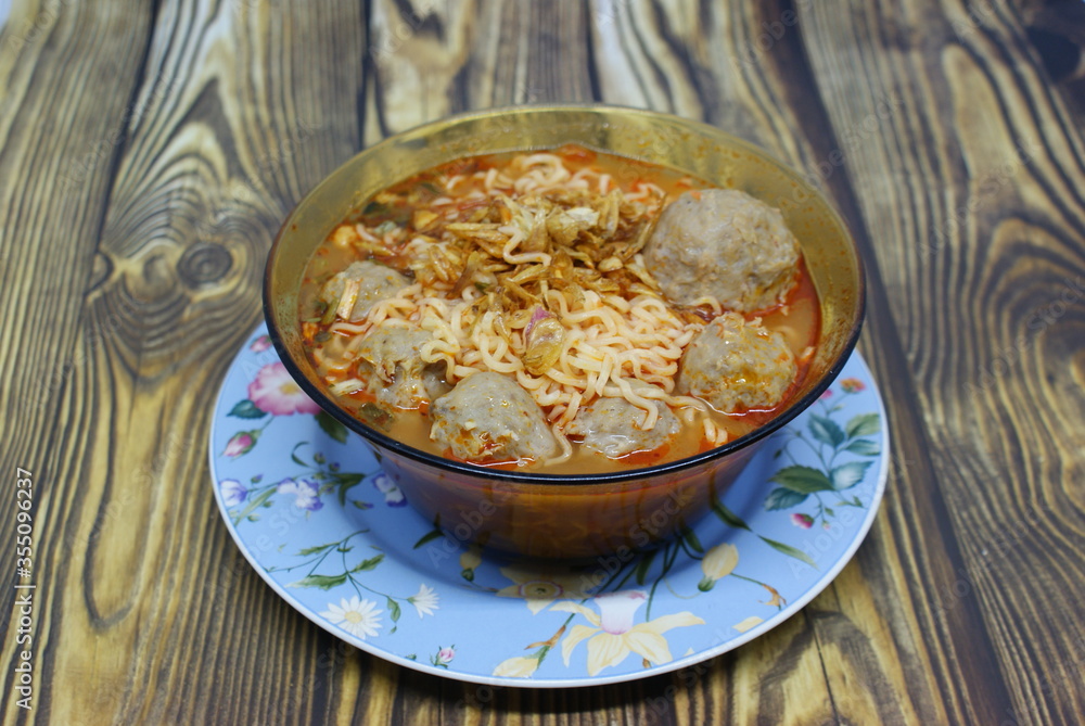 Indonesian traditional meatballs or bakso. Soup containing meatballs, noodles isolated on wood background