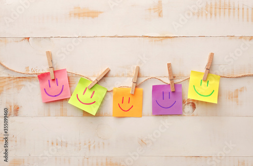 Papers with drawn happy faces on white wooden background