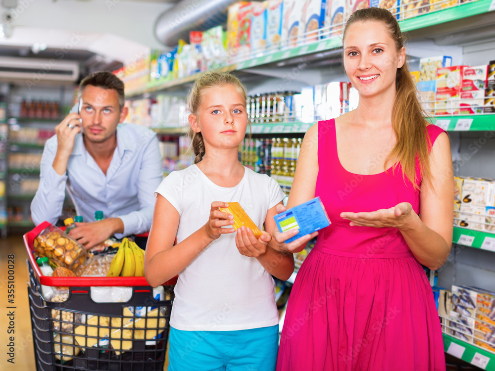 Cheerful woman and teenager girl in the grocery shop. male on backdrop
