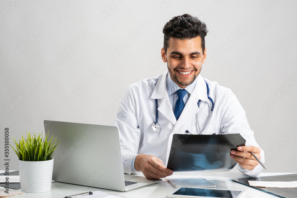 Handsome young doctor looking at x-ray scan Handsome young doctor looking at x-ray scan
