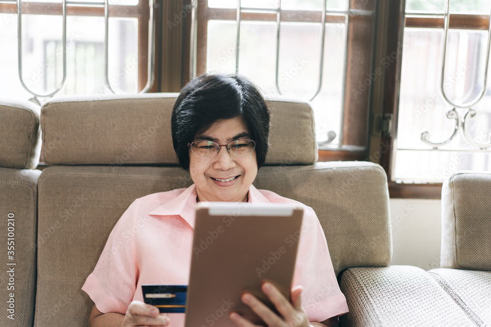 Asian elderly woman with technology use credit card for shopping online.