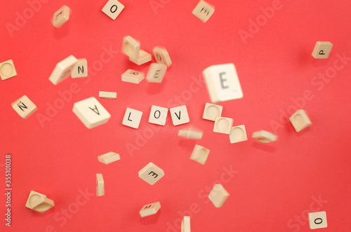 red background with scrabble pieces with the word love and pieces falling photo