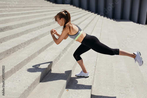 The Pilates trainer performs an exercise on the stairs with a stand on one leg, arms extended and the other leg to the sides.