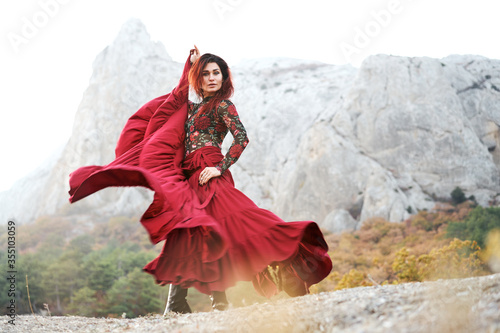 Woman in red long dress dancing on mountains view