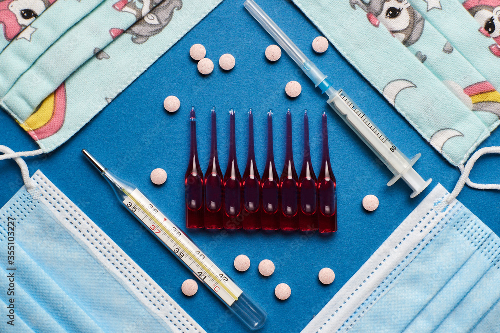 Prevent coronavirus. Medical mask, thermometer, vitamins, syringe on blue background. Prevent coronavirus. Medical mask, thermometer, vitamins, syringe on blue background.