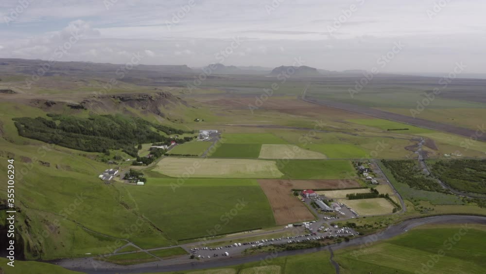 Aerial lockdown shot of vehicles by stream against cloudy sky, drone flying over green landscape - Southwestern Iceland, Iceland Aerial lockdown shot of vehicles by stream against cloudy sky, drone flying over green landscape - Southwestern Iceland, Iceland