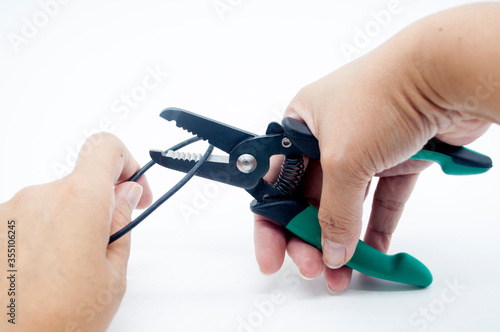 hand holding pliers cut a black cable isolated on white background