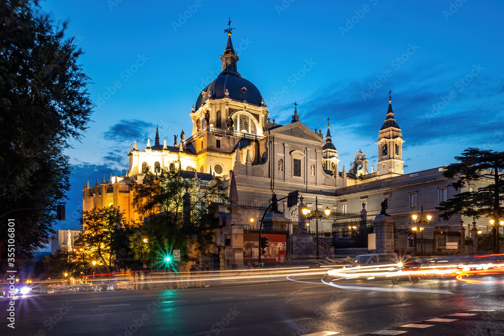Cathedral of Saint Mary the Royal of La Almudena in center of Madrid at night. View from the crossroad with car lights.