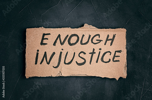 Enough injustice text on cardboard on dark background photo