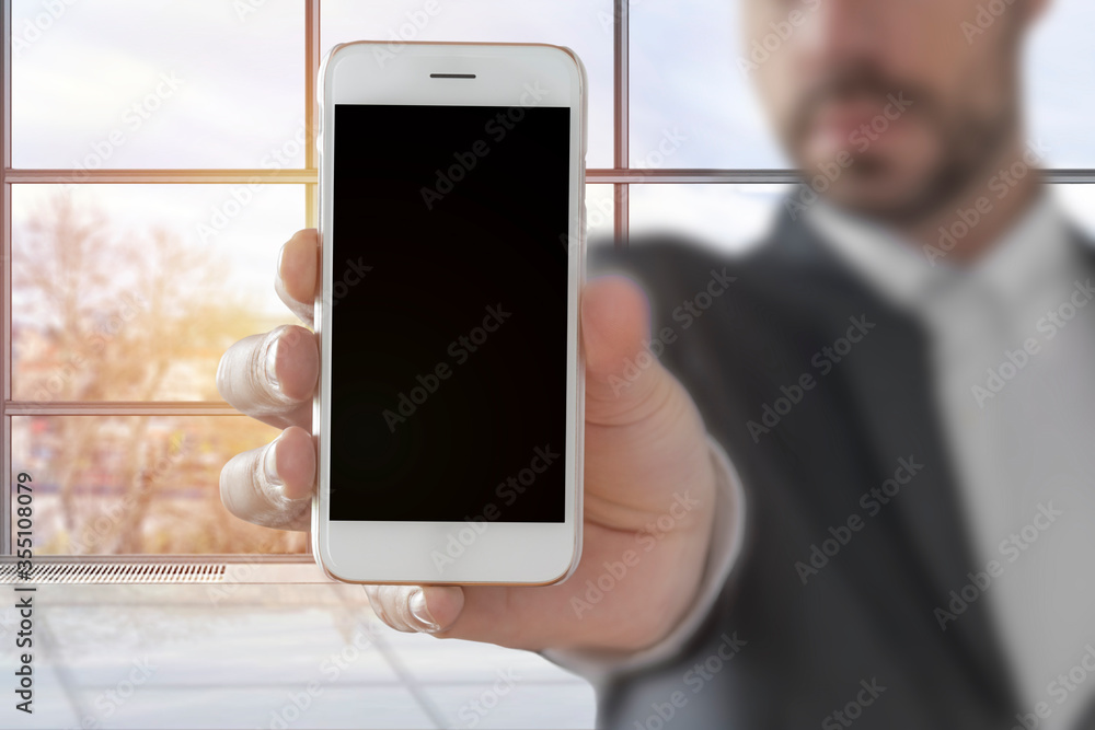Businessman showing smart phone, with copy space in the office Businessman showing smart phone, with copy space in the office