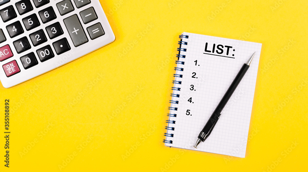 A notepad on a spiral with a list and numbered items lies on a yellow background with a calculator and pen, pencil. Layout of stationery. A notepad on a spiral with a list and numbered items lies on a yellow background with a calculator and pen, pencil. Layout of stationery.