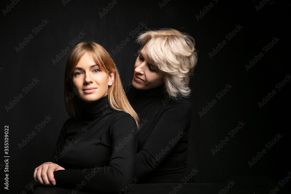Mom looks at her daughter. tender family photo. studio models on black background Mom looks at her daughter. tender family photo. studio models on black background