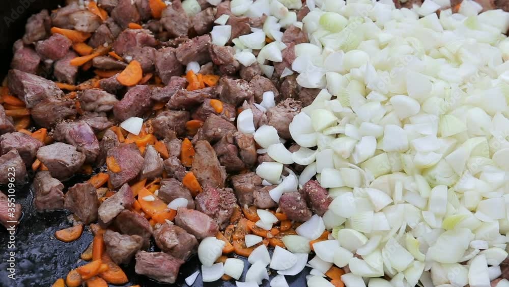 Cooking pork meat in big pan. Professional cook stirring and mixing vegetables and meat in big frying pan on outdoor culinary festival Cooking pork meat in big pan. Professional cook stirring and mixing vegetables and meat in big frying pan on outdoor culinary festival