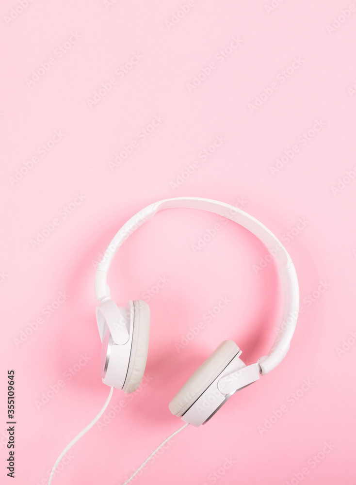 White headphones on pink background. Top view to the music. Around it is quiet, inside is loud. Respect for foreign borders. White headphones on pink background. Top view to the music. Around it is quiet, inside is loud. Respect for foreign borders.