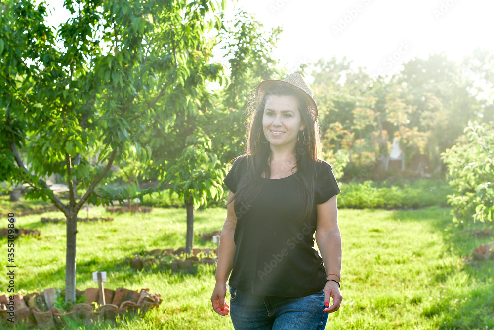 Smiling happy  young  woman gardener in an  organic  orchar apple garden in a sunny day