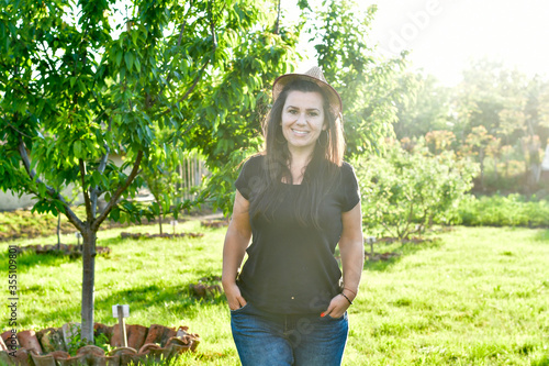 Smiling happy  young  woman gardener in an  organic  orchar apple garden in a sunny day photo