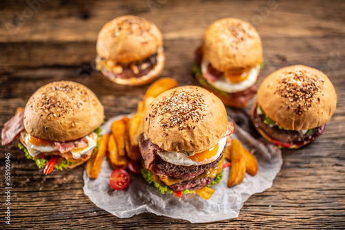 Selection of various fresh tasty burgers in sesame buns with potato wedges in a rustic environment