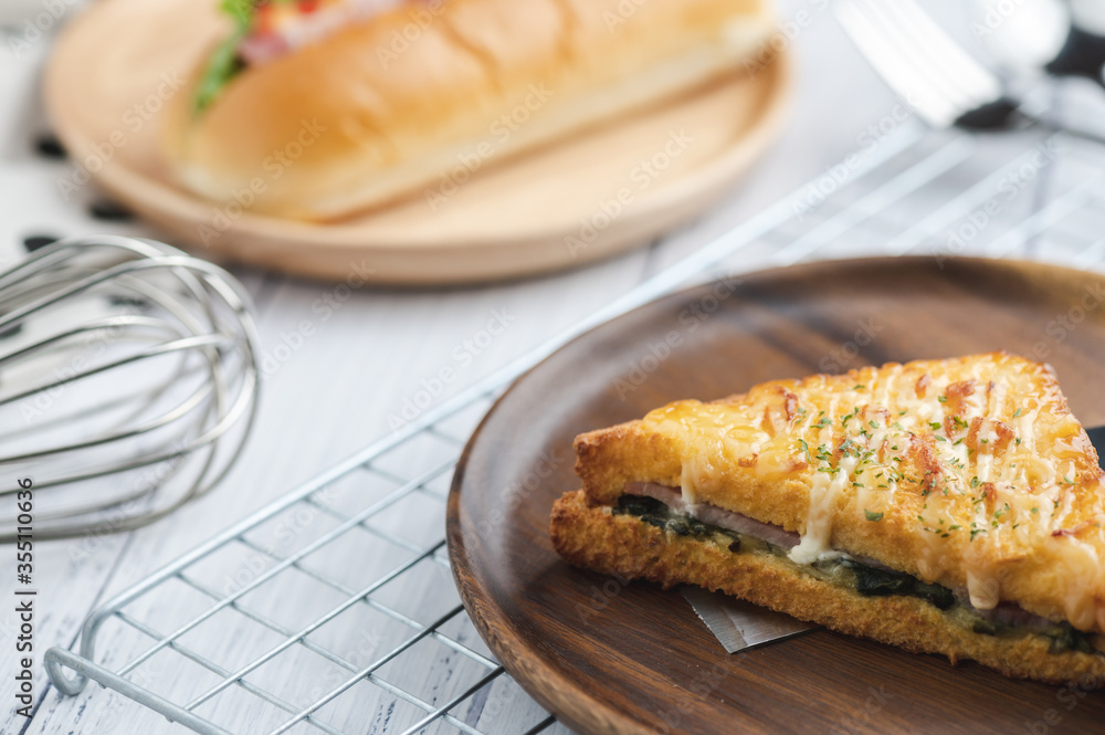 croque monsieur with slices of boiled ham, placed on a wooden plate with cooking tools. croque monsieur with slices of boiled ham, placed on a wooden plate with cooking tools.