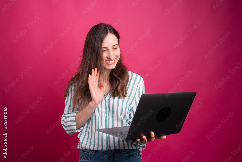 Photo of cheerful young woman holding laptop and saluting everyone in online conference Photo of cheerful young woman holding laptop and saluting everyone in online conference