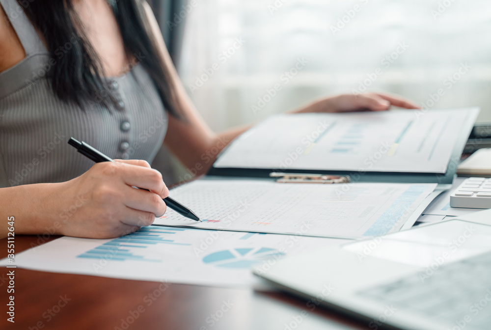 Business woman working from home with data document graph chart report on wooden desk. Home finances, investment, economy concept. Business woman working from home with data document graph chart report on wooden desk. Home finances, investment, economy concept.