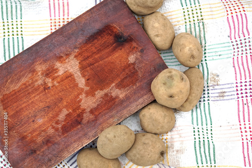 Empty wood cutting board with some potato around