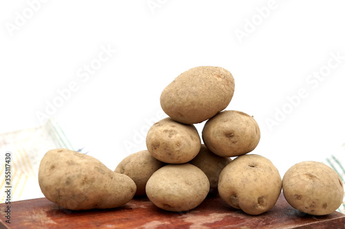 Pile of unpeeled potatoes above wood cutting board