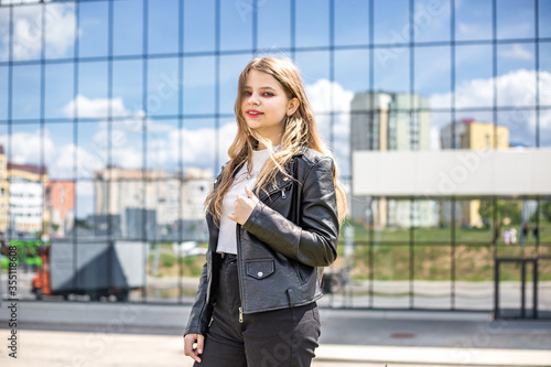 young blonde schoolgirl in black leather jacket posing in the parking lot