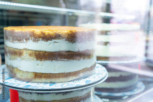 Fresh sponge cake with cream on the sideboard behind the glass