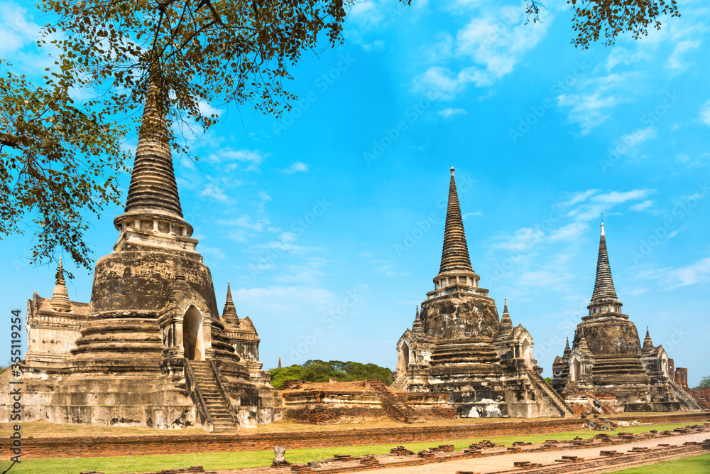 Fototapeta premium Historical architecture of Thailand - ruins of old Siam capital Ayutthaya. View to three white chedies of Wat Pra Si Sanphet temple