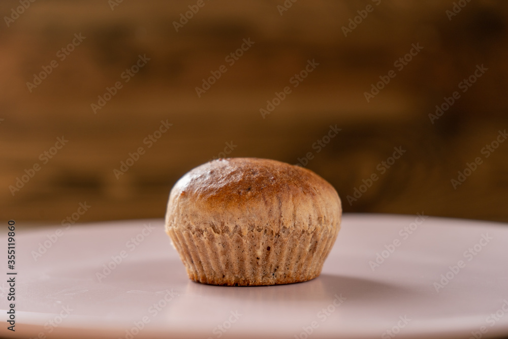 Fresh chocolate cupcake on a pink plate on the wooden background Fresh chocolate cupcake on a pink plate on the wooden background