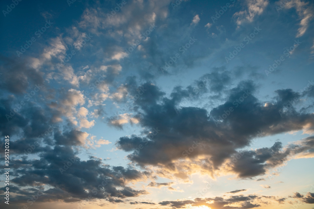sun sets behind the clouds in the blue evening sky as a natural background sun sets behind the clouds in the blue evening sky as a natural background