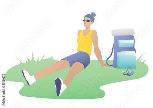 A young beautiful girl with glasses sits in a clearing and enjoys camping. The concept of outdoor recreation. Blue and yellow design.Blueandyellowdesign.