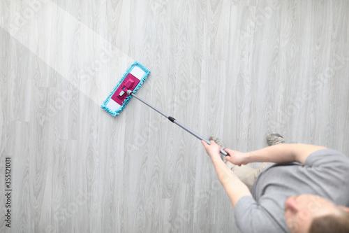 Male hant hold plastic mop and wash dirty ploor closeup background. Professional cleaning concept photo