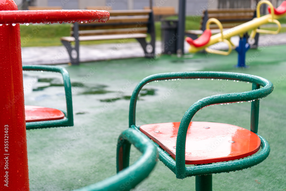 Nobody on the wet red and green carousel on the playground after rain. Close-up Nobody on the wet red and green carousel on the playground after rain. Close-up