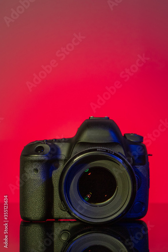 Camera with lens mounted on red background on glas panel