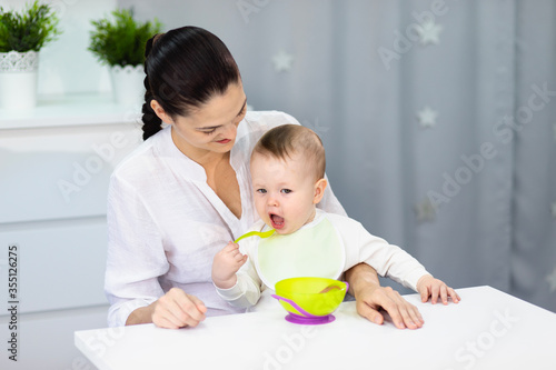 A young mother teaches her little son to eat false himself