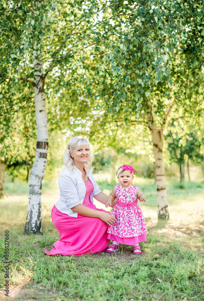 Naklejka premium Beautiful mother playing with baby girl in nature in summer