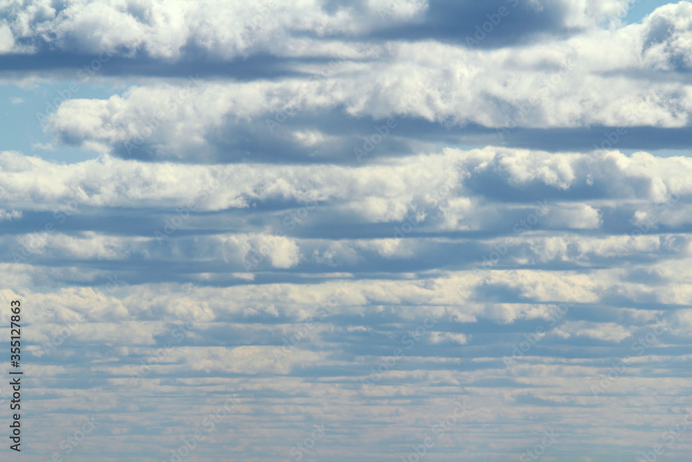 White fluffy clouds on a background of blue sky in summer. The concept of weather and climate White fluffy clouds on a background of blue sky in summer. The concept of weather and climate