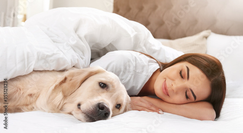 Young woman and her Golden Retriever on bed at home, banner design. Lovely pet