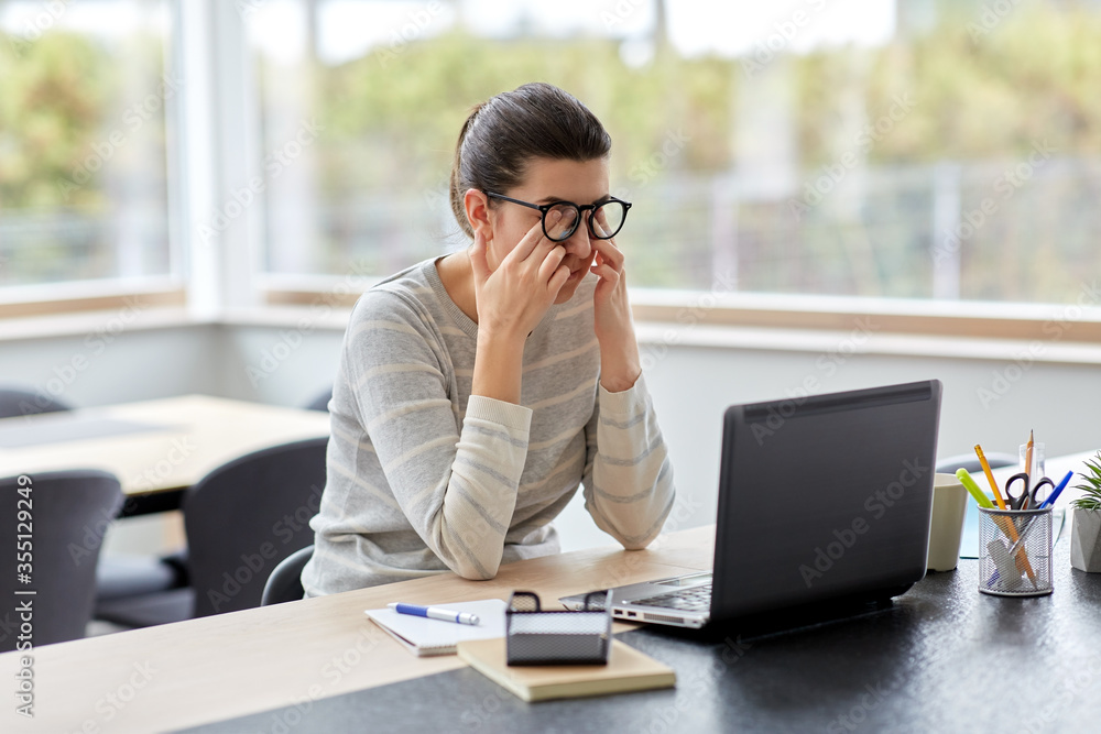 remote job, business and vision concept - tired young woman in glasses with laptop computer working at home office and rubbing her eyes remote job, business and vision concept - tired young woman in glasses with laptop computer working at home office and rubbing her eyes