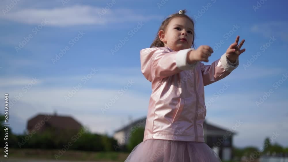 Toddler girl in pink raincoat on blue sky background portrait. Happy carefree free child Toddler girl in pink raincoat on blue sky background portrait. Happy carefree free child