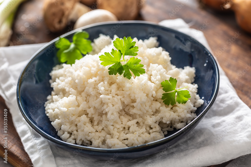 Bowl of steamed rice with mushrooms and leaks in the background Bowl of steamed rice with mushrooms and leaks in the background