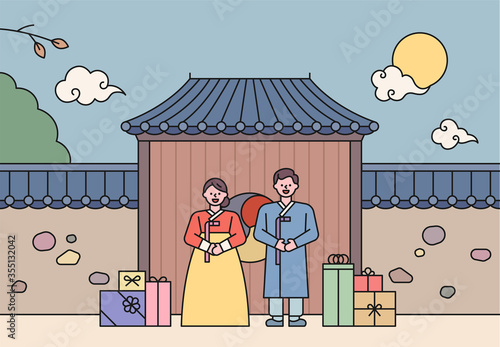 A couple in traditional Korean costumes are standing in front of a traditional house and greeting them. Gift boxes are stacked next to each other. flat design style minimal vector illustration.