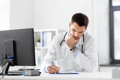 healthcare, medicine and people concept - stressed male doctor with clipboard at hospital