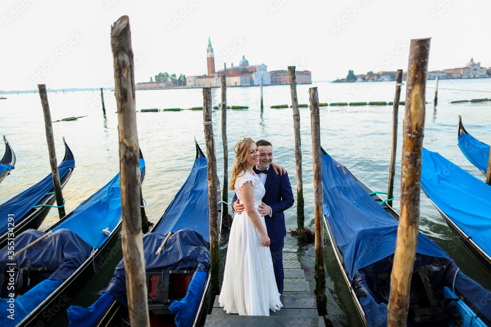 beautiful wedding couple posing on dock near blue gondolas