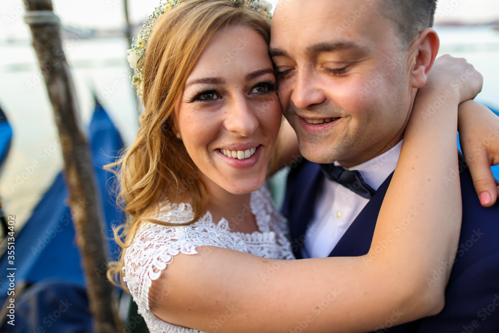 beautiful wedding couple posing on dock near blue gondolas beautiful wedding couple posing on dock near blue gondolas