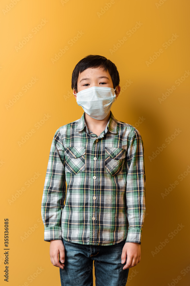 adorable asian boy in medical mask on yellow during self isolation adorable asian boy in medical mask on yellow during self isolation