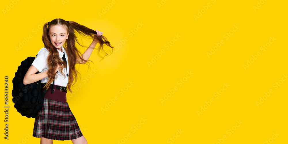 Elementary schoolgirl with backpack on vibrant yellow background, pupil in uniform, banner format, education concept