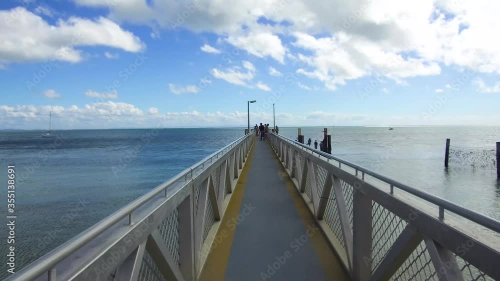 Walking Along Long Steel Pier Towards Ocean On A Clear Day With Blue Sky And Clouds In Australia Walking Along Long Steel Pier Towards Ocean On A Clear Day With Blue Sky And Clouds In Australia