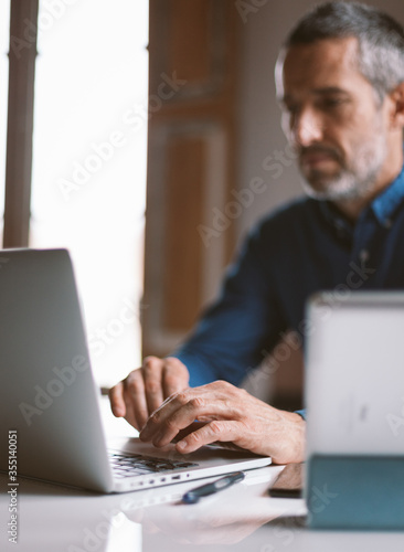 Closeup on male hands typing on laptop keyboard. Businessman working remotely from home or coworking place